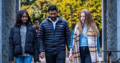 Two female and one male student walking on campus together, with yellow autumn leaves in the background.