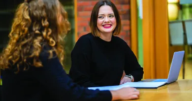 Two female students speaking at a desk