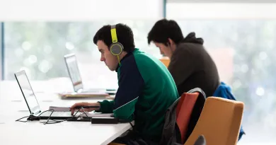 two students working at laptops