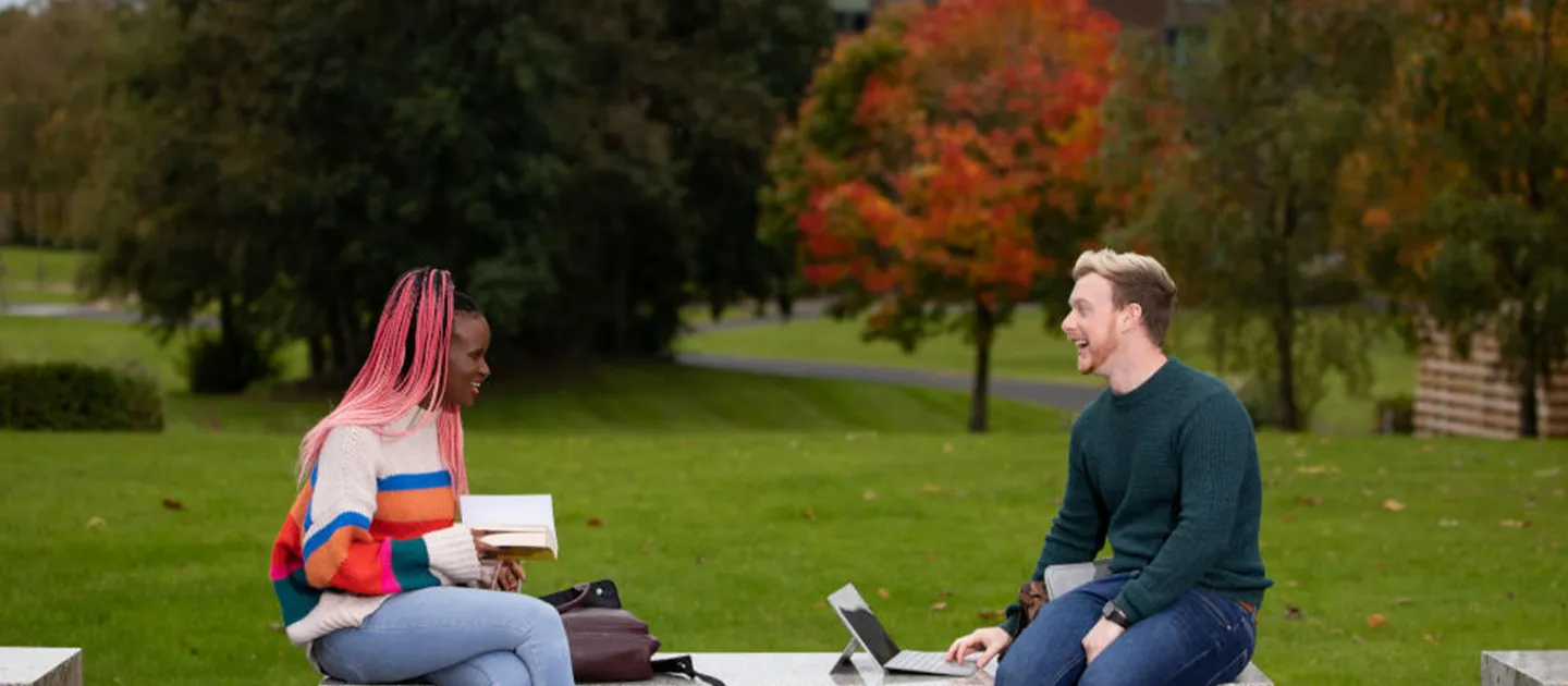 students chatting on a bench on campus 