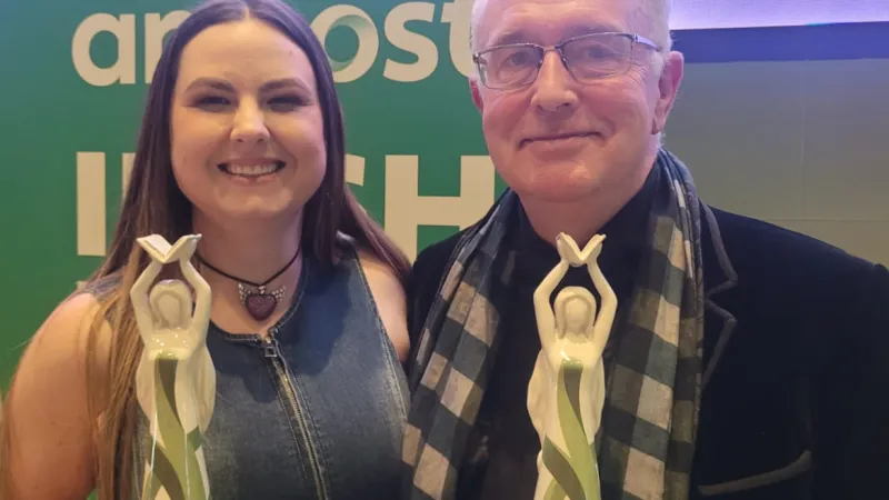UL graduate and guest lecturer, Gráinne O'Brien, and UL Professor of Creative Writing, Joseph O'Connor at the An Post Irish Book Awards. They are both smiling as they hold their awards - a green and white sculpture of a women with her arms raised.