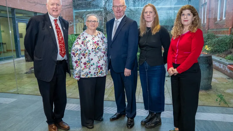 Two men and three women in professional attire stand smiling at the camera.