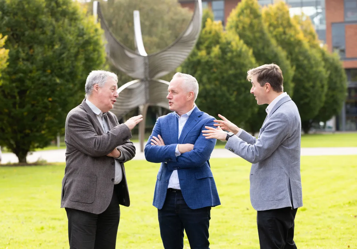 image of three men talking to each other in an outdoor setting 