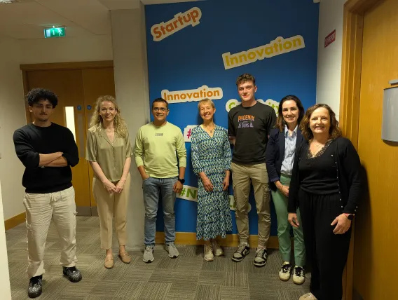 Group of men and women standing in front of spin out innovation signs