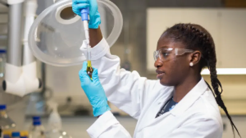 science student in lab coat  working on research in UL