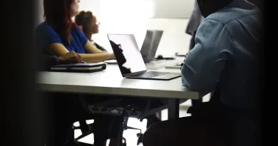 stock image of 4 people around a table with laptops
