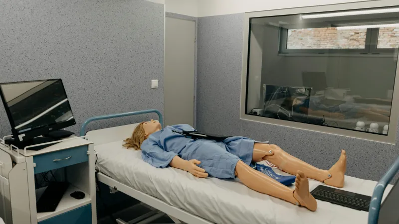Dummy in surgery dress on a bed in an simulate hospital theatre environment in front of an observation window