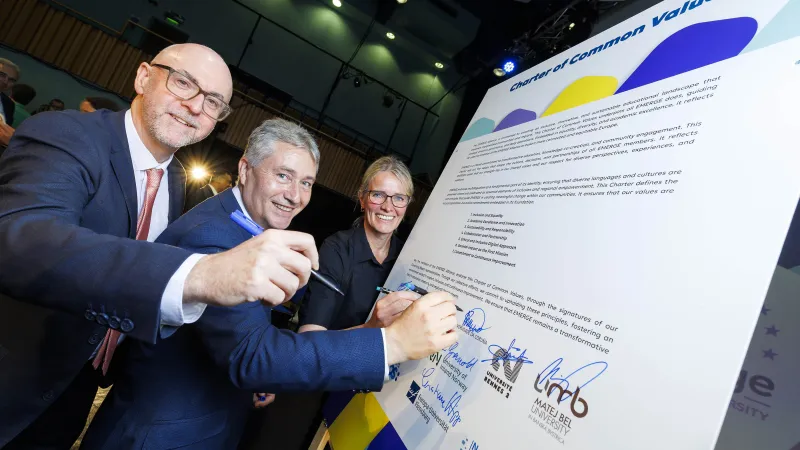 Three people sign a large white board - they are VP Global & Community Engagement UL, Prof Colin Fitzpatrick, Prof Ricard Cao Abad, University of A Coruna and Prof Stine Grønvold, Inland University Norway