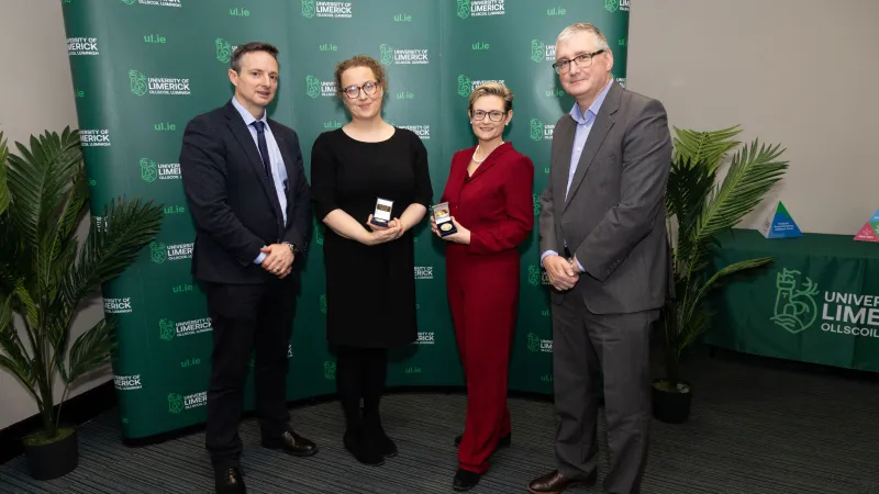 A picture of four people standing in front of a green UL banner at the research excellence awards