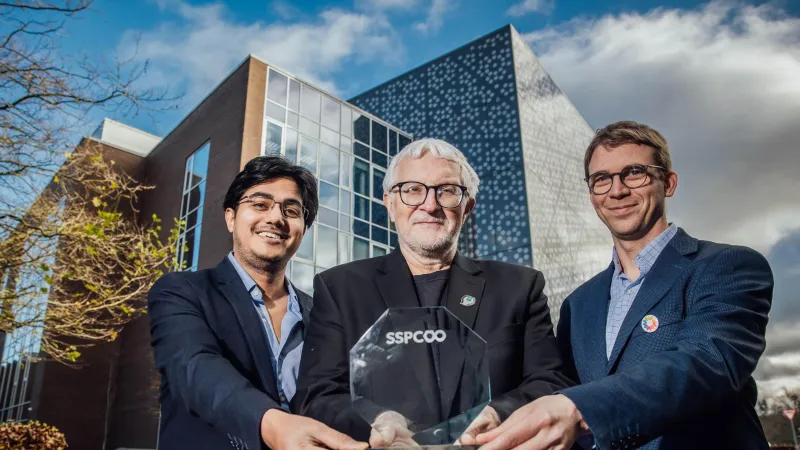 Soumya Mukherjee, Mike Zawototko, Matthias Vandichel holding glass award, standing in front of Analog Devices Building in UL